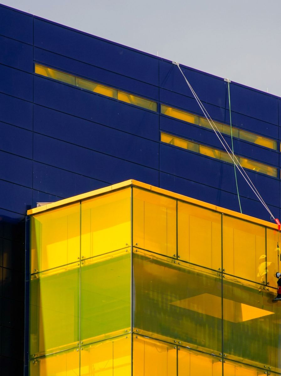 Yellow translucent glass cube extension protruding from a deep navy modern building facade